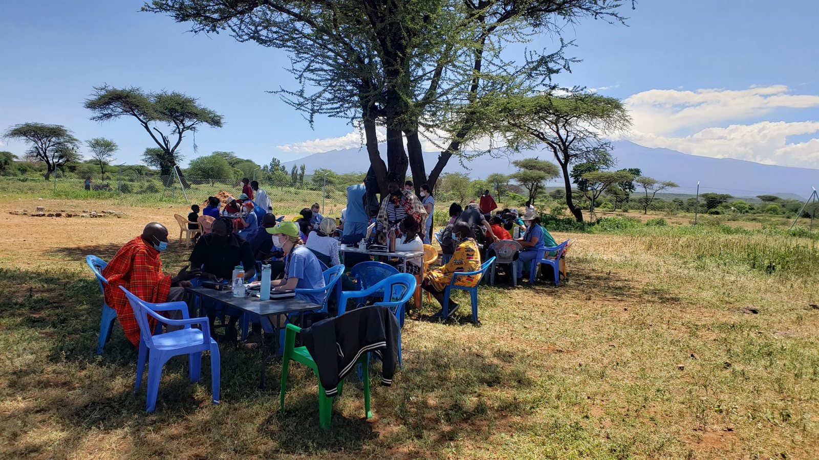 An outreach team meeting under an acacia tree on the Kajiado plains