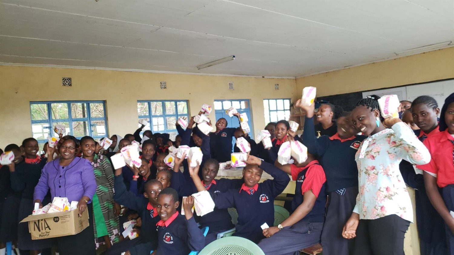 Smiling schoolgirls in Kajiado hold up sanitary pads donated by Entepesi Kenya